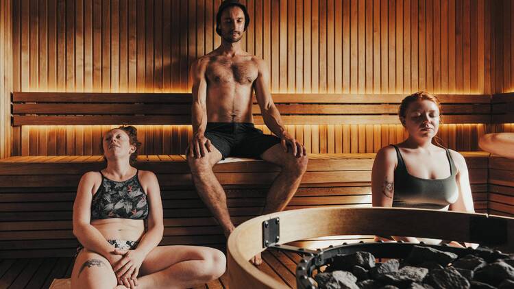 Three people sitting in a sauna room