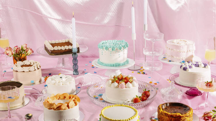 Intricately decorated assortment of colourful sponge cakes on a pink satin background.