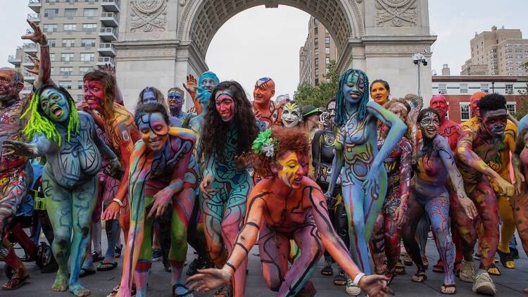 A group of bodypainted people in front of the Washington Square arch.
