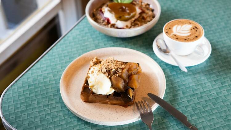 Apple crumble waffles and a cappuccino on a table