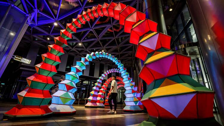 A person standing in the middle of a colourful archway installation.