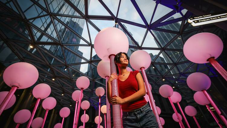 A woman standing among an illuminated installation featuring lamp posts.