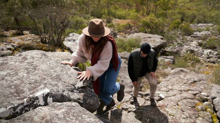 A man and a woman climb some rocks