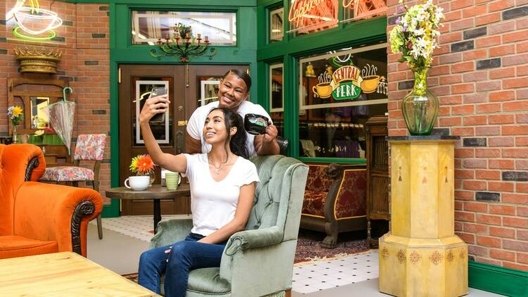 Two people pose carrying a couch down a staircase