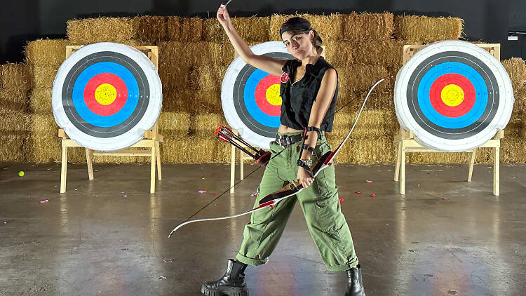 Kendall Tichner holds a bow and arrow inside Wild Captives studio. 