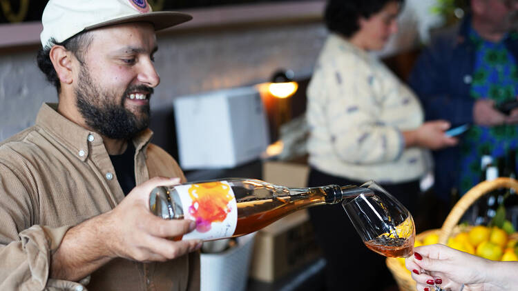 Bartender pouring wine at Poodle Bar and Bistro with a basket of lemons in the background.