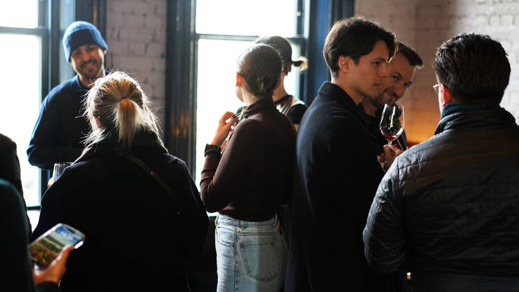 People gathering together at a wine tasting event in a sunlit bar.
