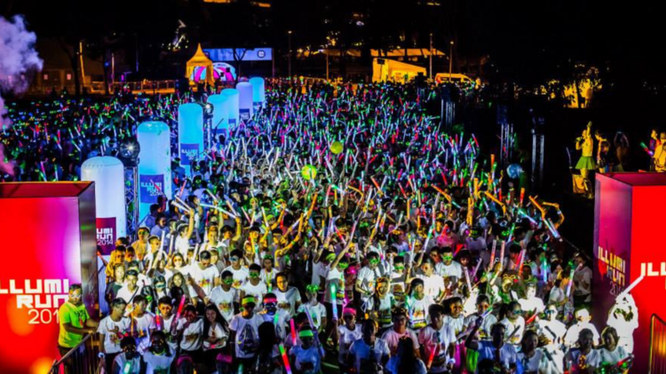 A big group of runners at the finish line of a neon fun run