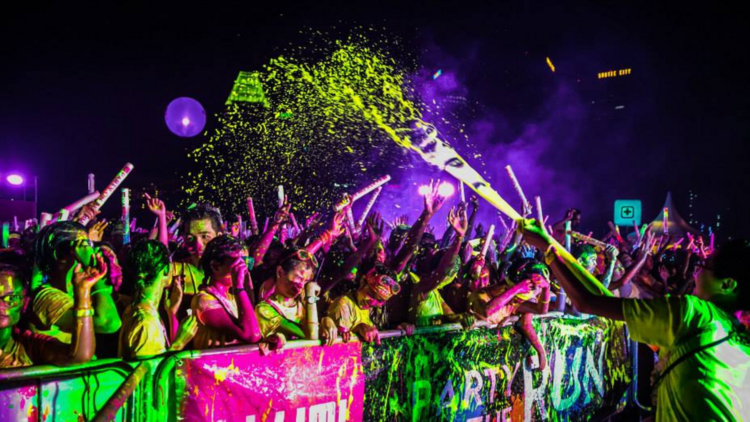 A big group of runners at the finish line of a neon fun run