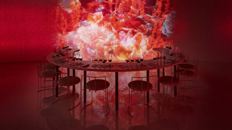 A semi-circle table with wine glasses set against a backdrop of digital art.