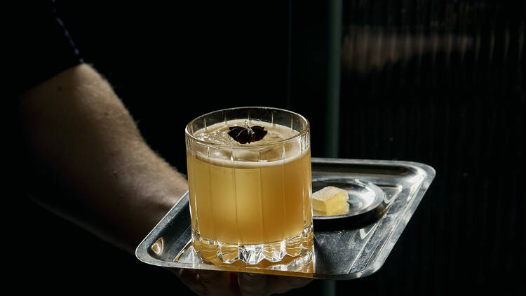 Bartender carrying a cocktail on a silver tray.