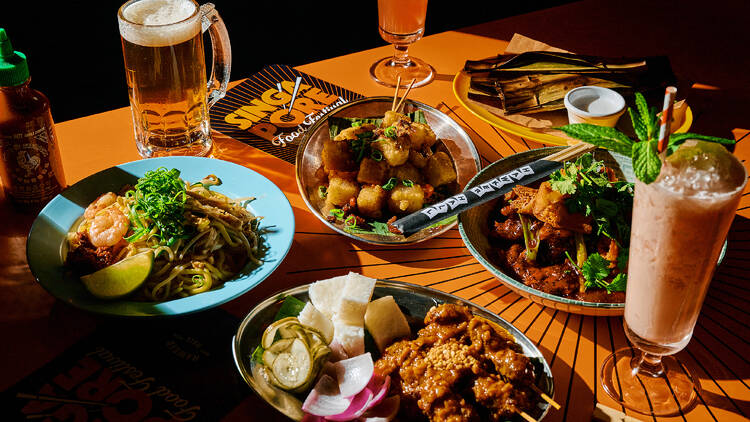 Assorted Singaporean-style eats lai out on a table with drinks.