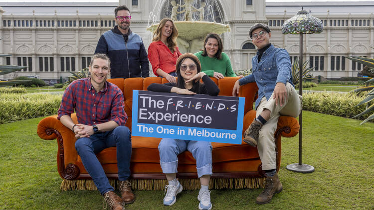 A group of people pose on a couch out the front of the Royal Exhibition Building.