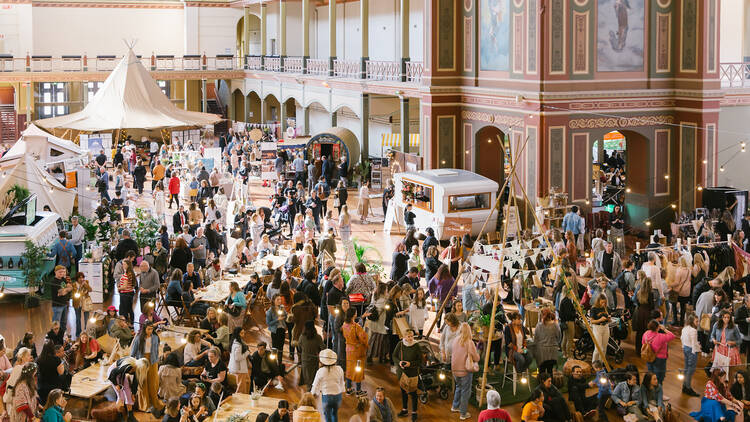 A photo of a market with lots of people inside the Royal Exhibition building. 