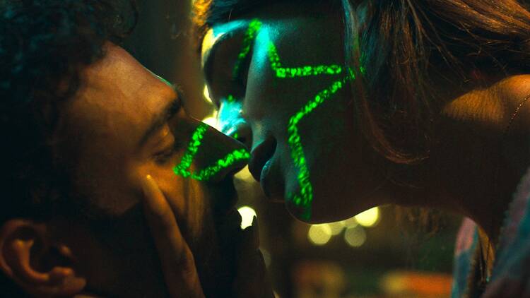 Two people kiss with a green star light illuminating their faces.