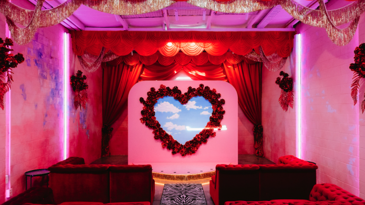 The inside of a wedding chapel with red curtains, red velvet seats and a love heart in the centre. 