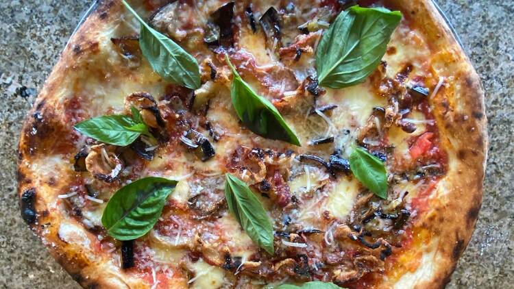 Pizza with basil leaves, cheese and other toppings.