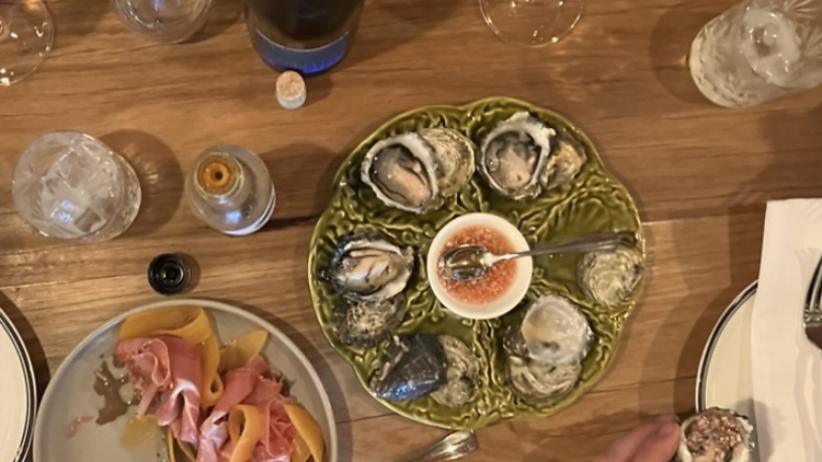 Assorted dishes, including oysters, and glasses of wine.