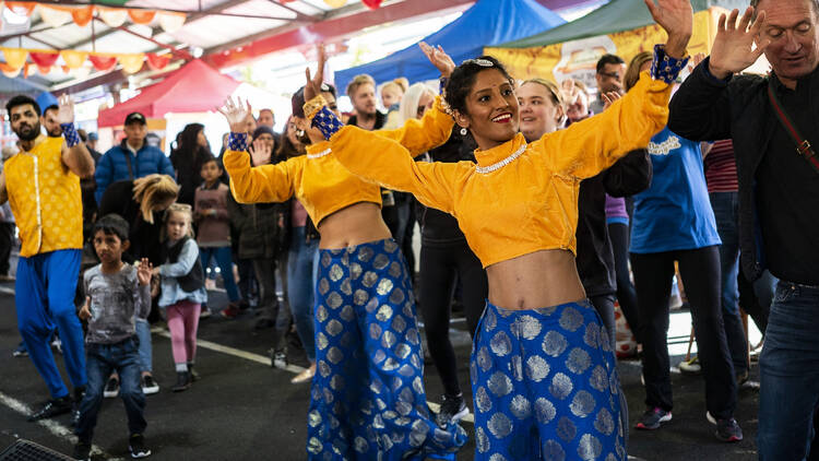 Women in traditional Indian clothing perform a dance. 