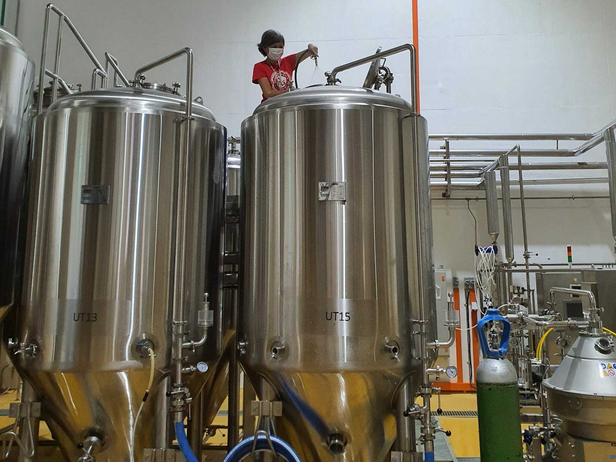 Brewer Kim Wong scaling the fermenting tanks in the brewery