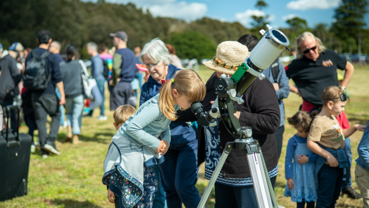 A girl looking through a microscope in a park