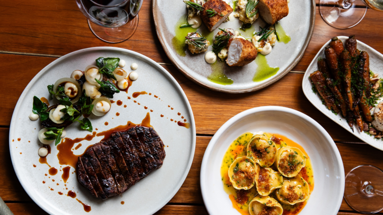 A food spread with steak, pasta and wine