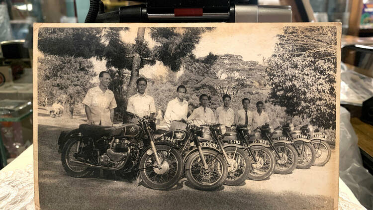 Item #9: Old black-and-white photo: men riding bikes with S plates, showcasing camaraderie in olden bike riding culture