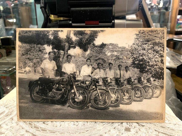 Item #9: Old black-and-white photo: men riding bikes with S plates, showcasing camaraderie in olden bike riding culture