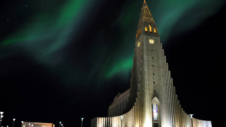 Hallgrimskirkja church with green northern lights (Aurora borealis) in Reykjavik, Iceland. Famous scandinavian cathedral at night, northern lights above.