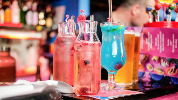 Bright pink and blue cocktails sitting on the bar. 