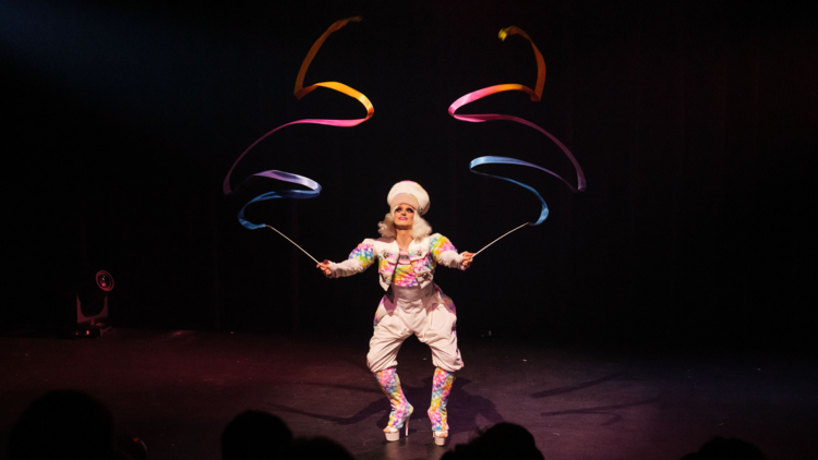 A drag queen with rainbow twirling sticks