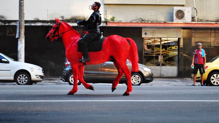 picture of a man riding a red horse through the streets