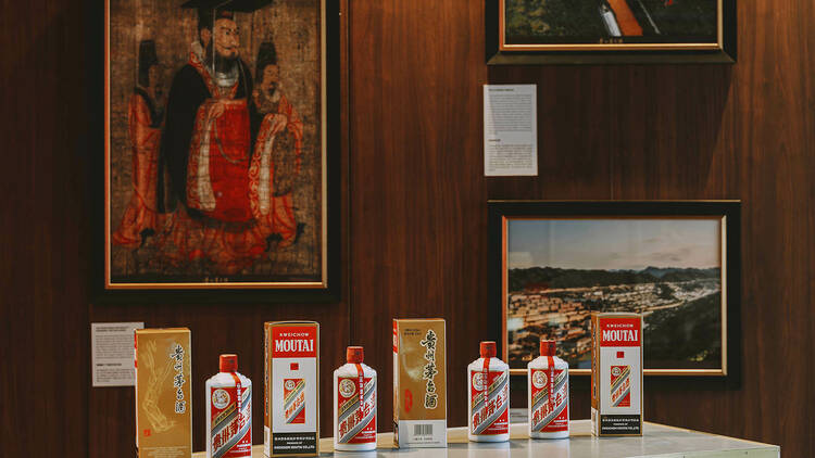 Bottles of Moutai on a table with paintings in the background.