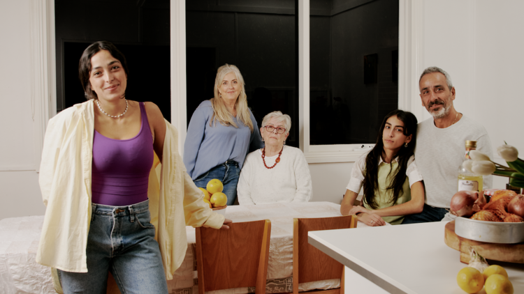 A family stand in the kitchen looking at the camera. 