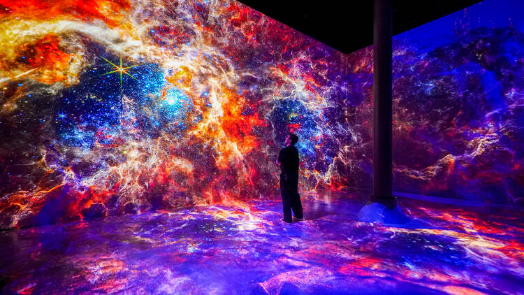 A man stands at an installation inside ARTECHOUSE.