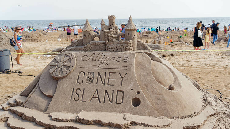 A sand castle reading Alliance for Coney Island.