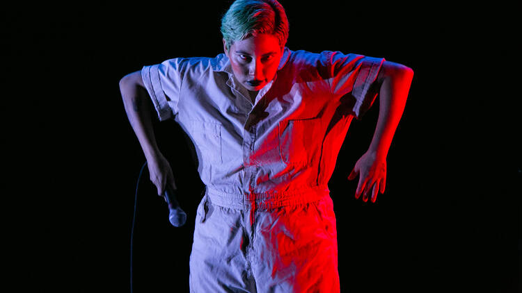 A performer in a jumpsuit holding a mic.