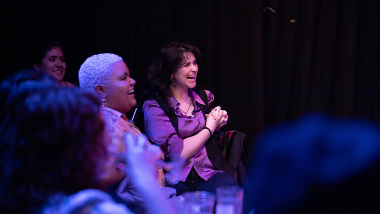 Two women laugh during a comedy show.