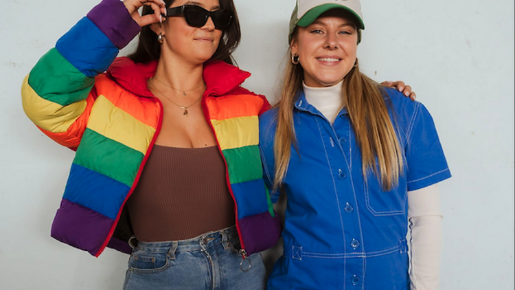 Two young women dressed in colourful clothing and smiling. 