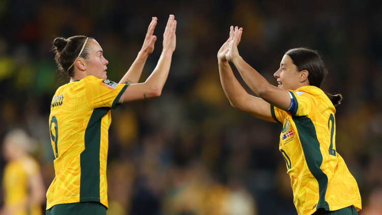 Two Matildas soccer players mid high five on the field