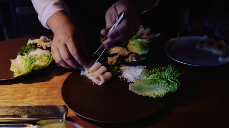 Chef plating up a dish with tweezers. 