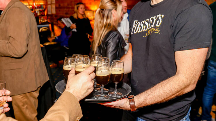 Fossey's bartender carrying a tray of whisky-based cocktails.