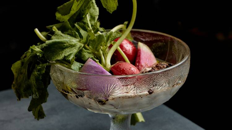 Elegant glass bowl containing radishes and a white sauce.