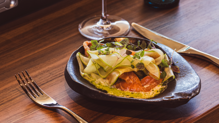 A ceramic bowl with salmon and salad