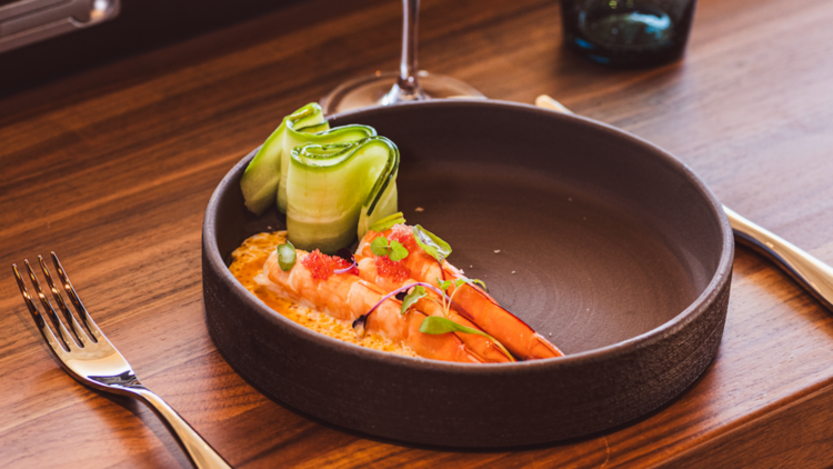 A ceramic bowl with prawns and cucumbers