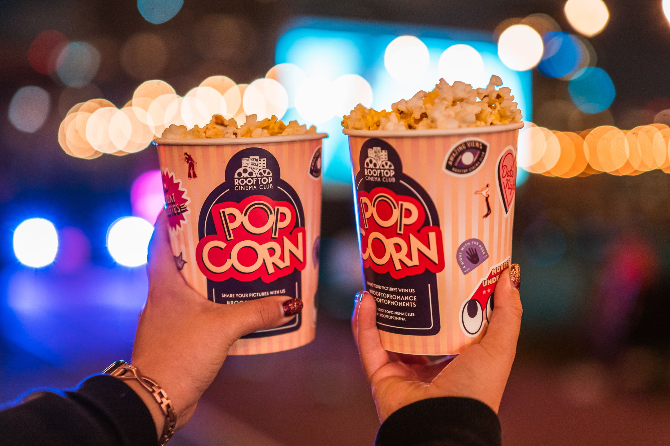 Two people hold up popcorn.