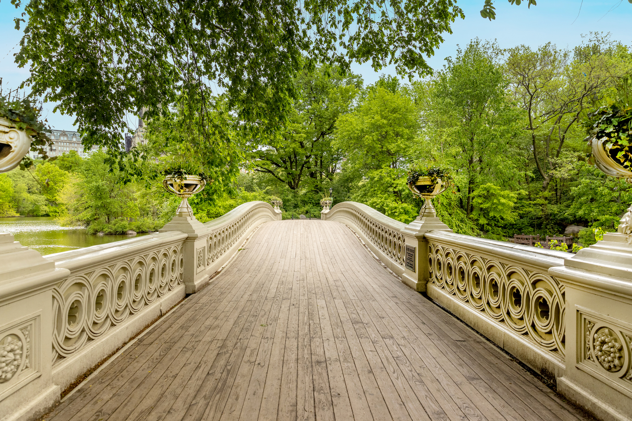 The Bow Bridge with green trees and a blue sky.