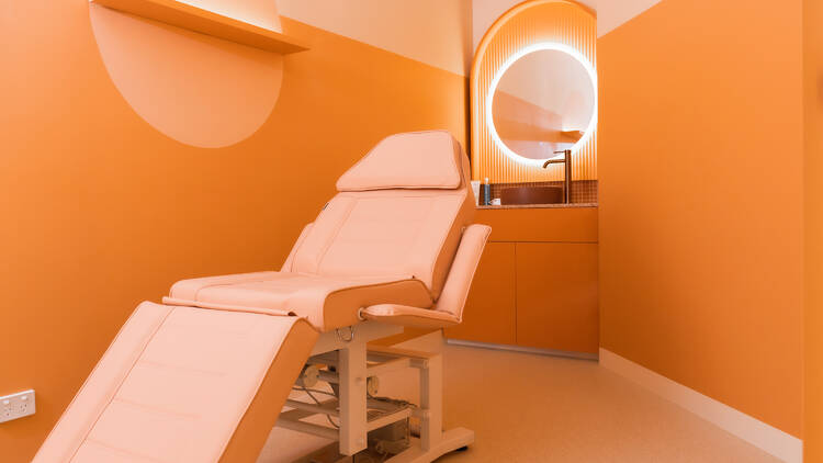 A bed in an orange room at a skincare clinic.