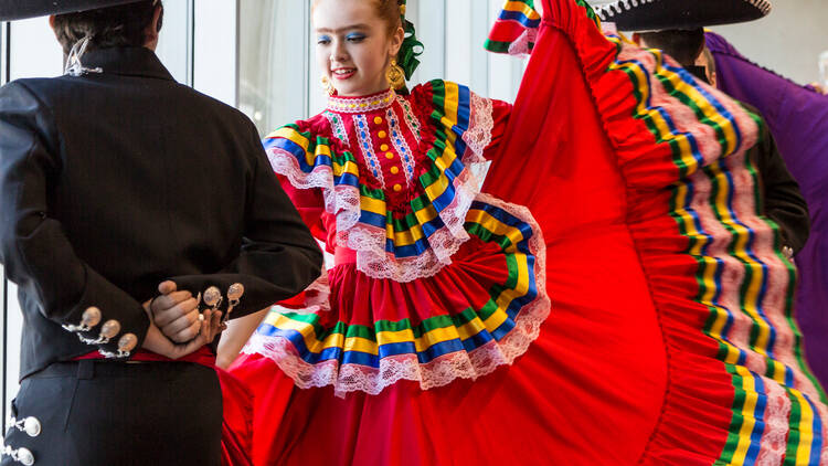 Niña bailando con traje típico color rojo y niño bailando con traje de charro 
