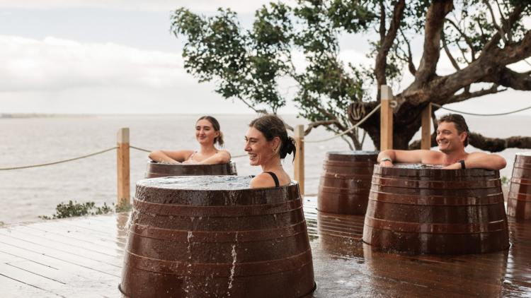 Three people in individual bathing barrels at Metung Spa